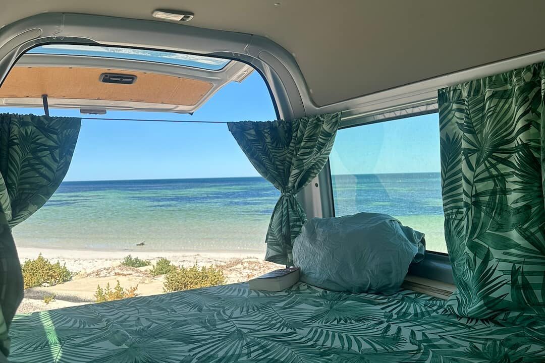 Looking at beach out of campervan to avoid campervan travelling common mistakes
