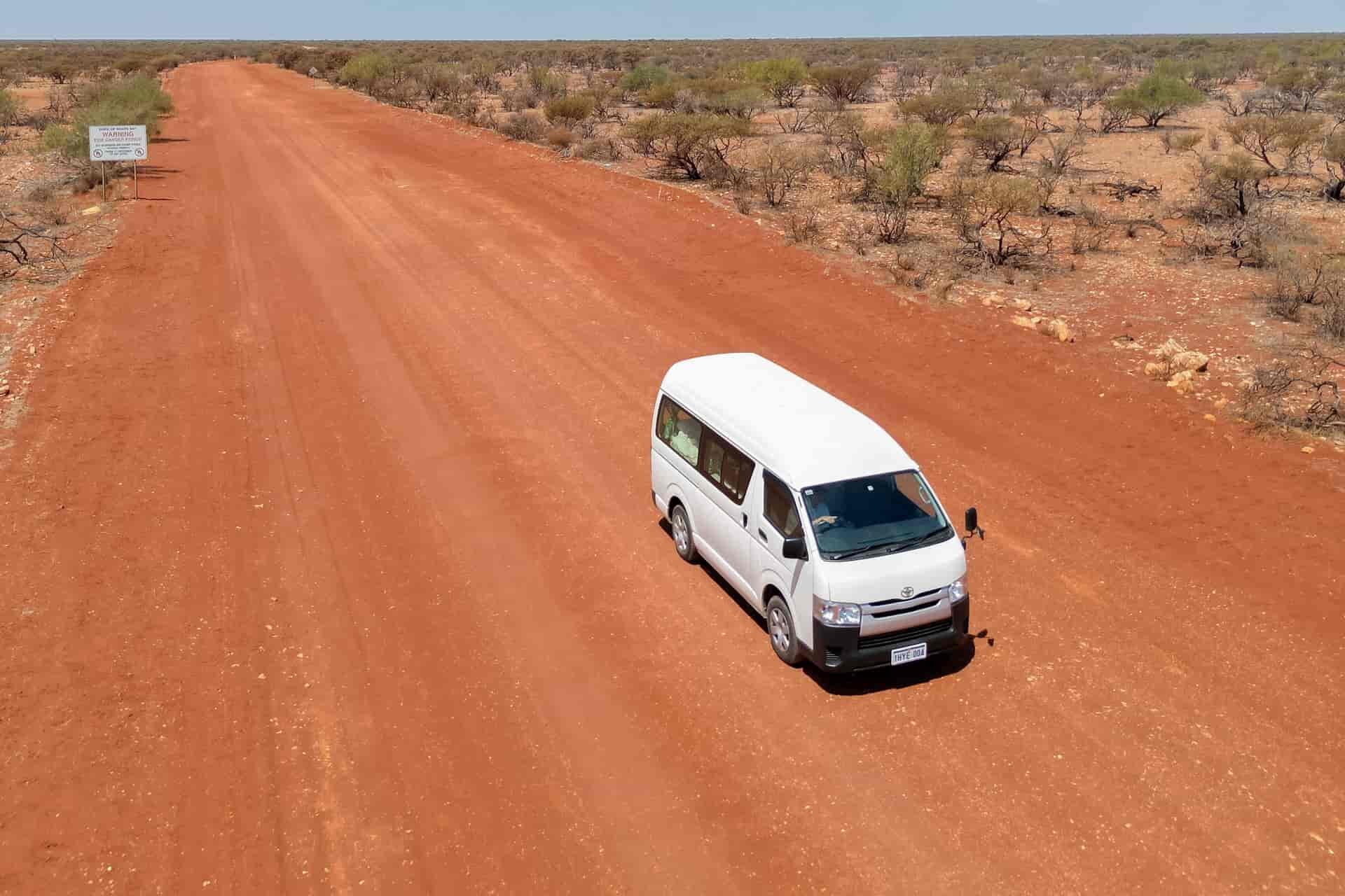 Drone shot of campervan driving in Western Australia on unsealed gravel road in the outback