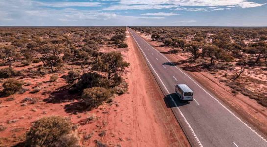 Drone shot of vast outback road in Western Australia with campervan driving on Perth to Exmouth road trip