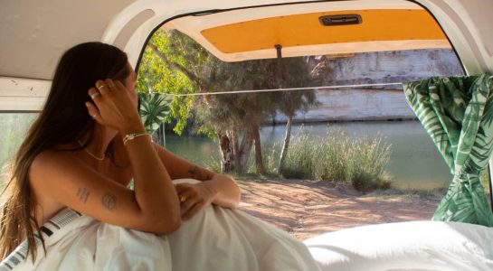 woman in back of campervan looking out while on summer road trip in wa